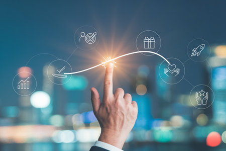 A hand in a suit jacket touches a glowing point on a curved line connecting various business icons like growth, target, gift, care, rocket, and star, set against a blurred city night background. This symbolizes progress and achievement.の素材