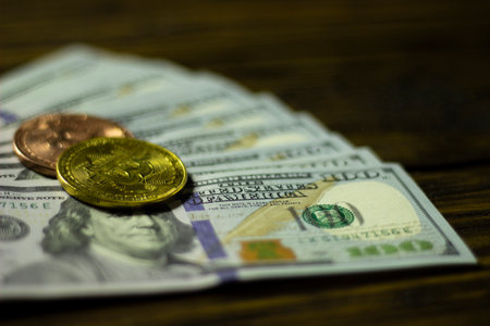 Bitcoin cryptocurrency coin and dollars on a wooden surfaceの写真素材