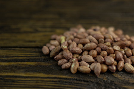 Raw peanuts on a rough wooden background.