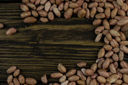 Raw peanuts on a rough wooden background.
