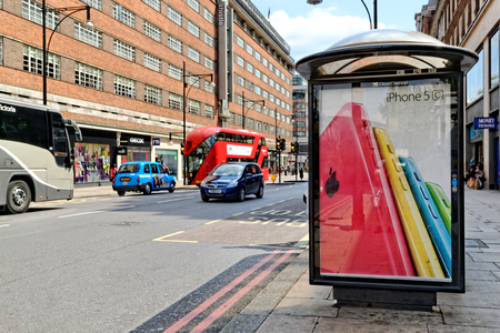 LONDON - JULY 1, 2014. Bus shelter with an advert of iPhone 5C on Oxford street, London. Oxford street is one of the busiest shopping places in the world.のeditorial素材