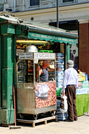 LONDON - JULY 1, 2014: Street vendor offers ice cold drinks and freshly roasted caramel peanuts at Oxford Street, where he competes with large supermarket chains.のeditorial素材