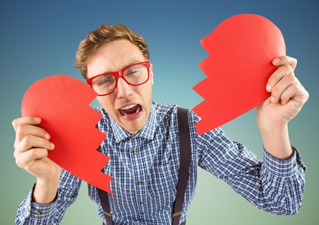 Crying man holding broken heart against blue backgroundの写真素材