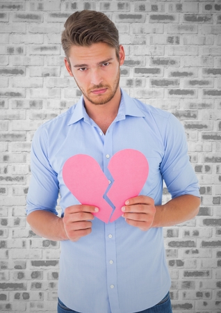 Portrait of depressed man holding broken heartの写真素材