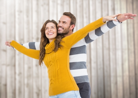 Happy couple pretending to fly against wooden backgroundの写真素材