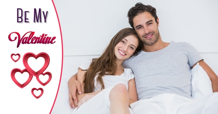 Composite image of smiling couple in bed with red heart shapes and valentine textの写真素材