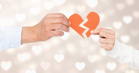 Hands of couple holding a broken heart against bokehの写真素材