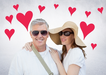 Mature couple standing and smiling against digitally generated background with heartsの写真素材