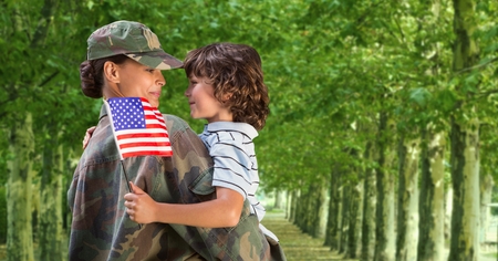 Army woman carrying her son while looking at each other at parkの写真素材