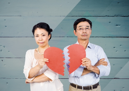 Sad couple holding broken heart against wooden background