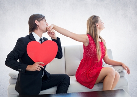 Man with red heart pleasing upset woman at homeの写真素材
