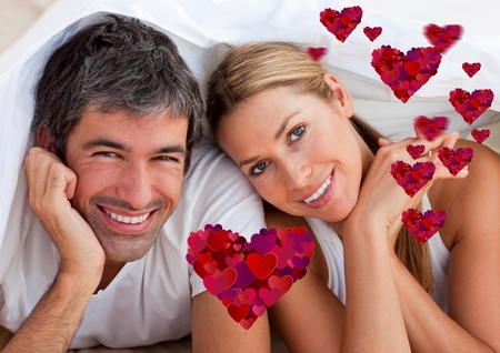 Portrait of digital composite of happy couple lying on bed at homeの写真素材