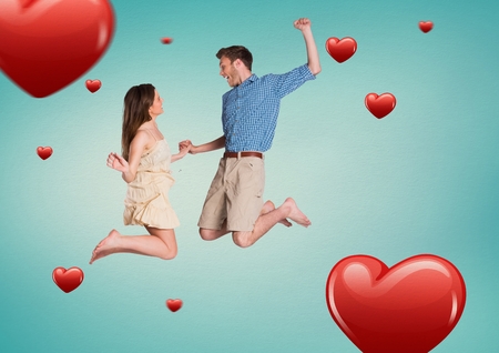 Happy couple jumping against digitally generated heart backgroundの写真素材