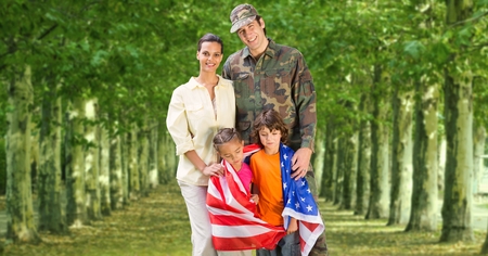 Happy family standing in park with american flag on a sunny dayの写真素材