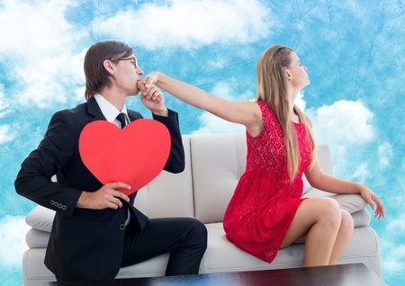 Man with red heart pleasing upset women against digitally generated sky backgroundの写真素材