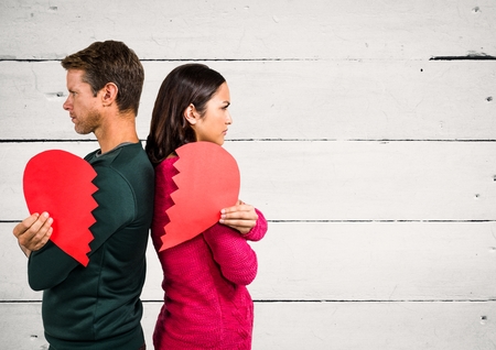 Angry couple holding broken heart against wooden backgroundの写真素材