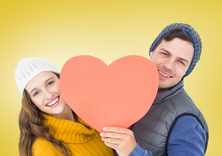 Happy couple holding heart against yellow backgroundの写真素材