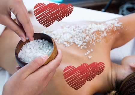 Woman getting sea salt massage on back with digitally generated heartの写真素材