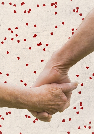 Hand of senior couple holding hands against digitally generated heart backgroundの写真素材