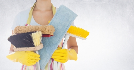 Mid section of woman holding various cleaning equipments against white backgroundの写真素材