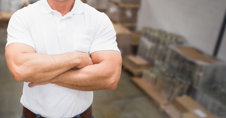 Mid section of supervisor standing with arms crossed in warehouseの写真素材
