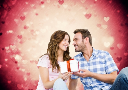 Composite image of romantic couple holding gift box against pink backgroundの写真素材