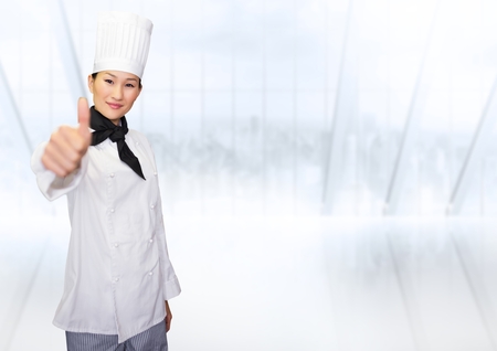 Portrait of smiling female chef cook showing thumbs up against white backgroundの写真素材