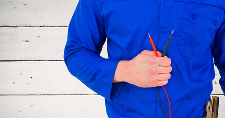 Mid section of handy man standing with cables against wooden backgroundの写真素材