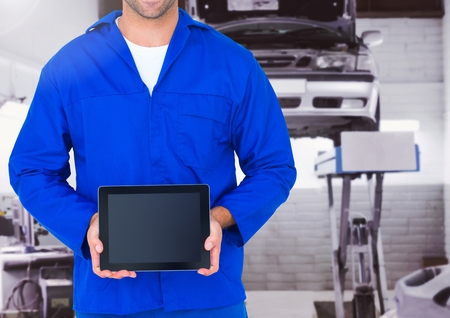 Mid section of mechanic holding a digital tablet at garageの写真素材