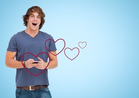 Excited man texting on mobile phone with digitally generated red heart against blue backgroundの写真素材