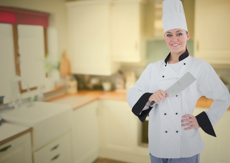 Portrait of female chef holding knife against digitally generated kitchenの写真素材