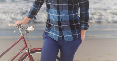 Mid section of man standing with bicycle on the beachの写真素材
