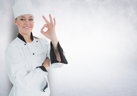 Portrait of smiling female chef cook showing ok sign against white backgroundの写真素材