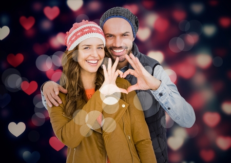 Portrait of smiling couple making heart shape with hands against digitally generated backgroundの写真素材