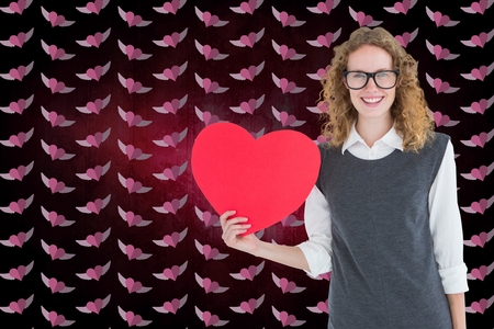 Composite image of nerd woman holding red heart against digitally generated backgroundの写真素材