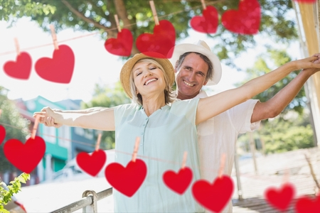 Composite image of red hanging hearts and happy mature couple dancingの写真素材