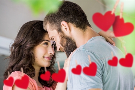 Romantic couple staring at each other with red hanging heartsの写真素材