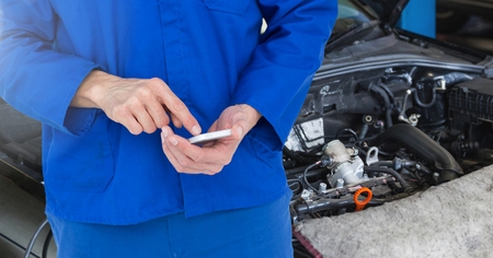 Mid section of car mechanic using mobile phone at garageの写真素材
