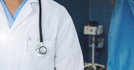 Mid section of doctor standing in operation room with stethoscopeの写真素材