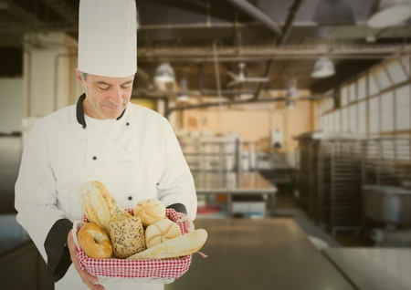 Smiling Male chef holding various bread loafs in bakeryの写真素材