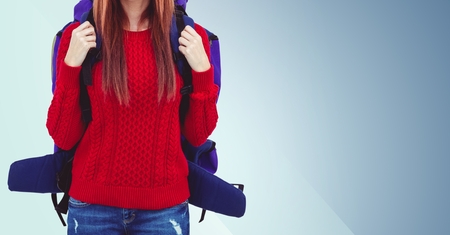Mid section of woman with backpack against blue backgroundの写真素材