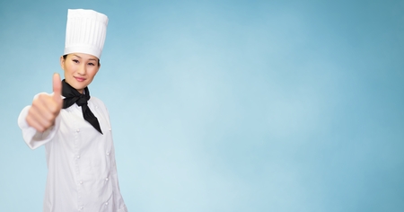 Portrait of smiling female chef giving thumbs up sign against wooden background