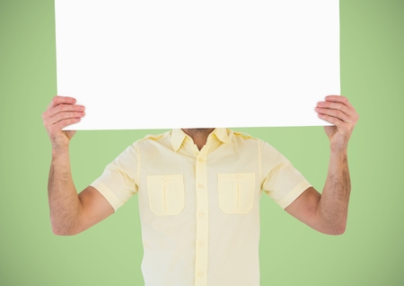 Digital composite of Man with large blank card over face against green backgroundの写真素材