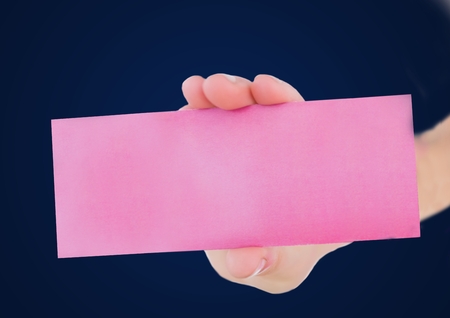 Digital composite of Hand with pink blank card against navy backgroundの写真素材