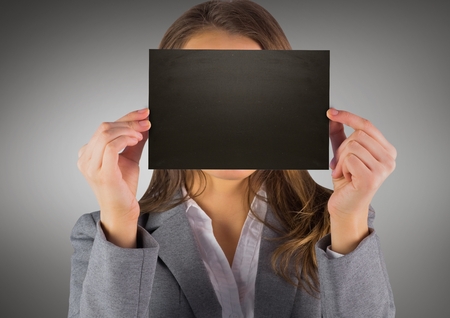 Digital composite of Business woman with black blank card over face against grey backgroundの写真素材