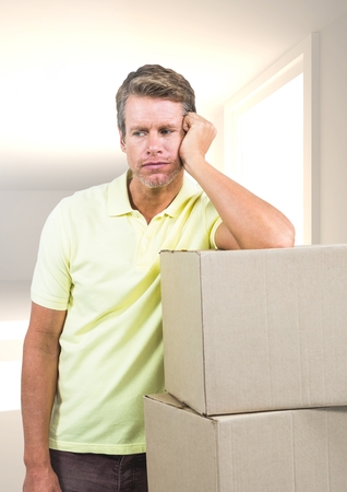 Digital composite of Sad man leaning on cardboard boxes against homeの写真素材