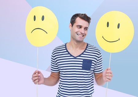 Digital composite of Man holding happy and sad face against blue backgroundの写真素材