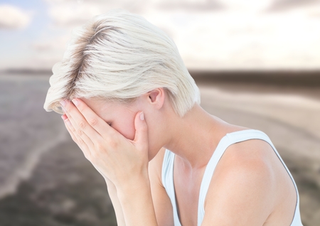 Digital composite of Sad woman with face in hands against sea landscapeの写真素材