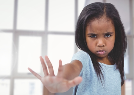 Digital composite of Angry Girl with hand out stopping against windowsの写真素材