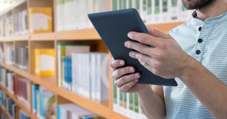 Digital composite of man on tablet in Libraryの写真素材